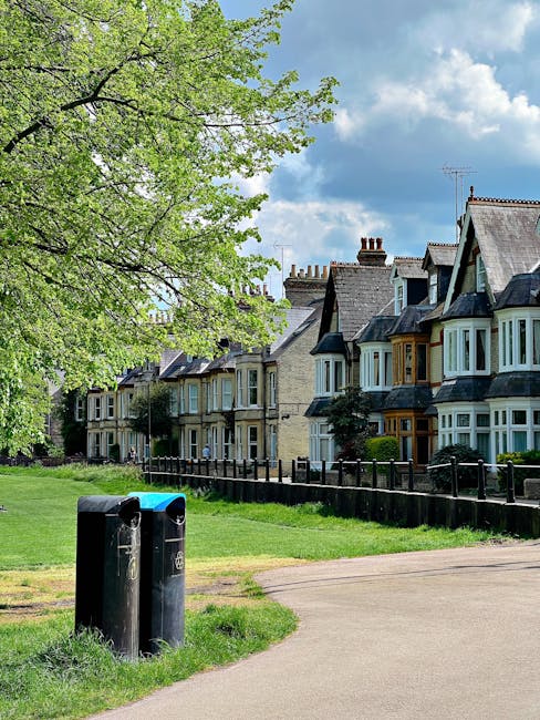 A residential street scene featuring a row of traditional Victorian-style terraced houses with bay windows, pitched roofs, and brick facades, some with chimney stacks visible. In the foreground, there